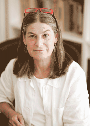 Headshot of Lisa Berkman with long graying hair, glasses, white blouse, and white jacket.