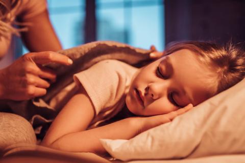 Photo of a child being tucked into bed.