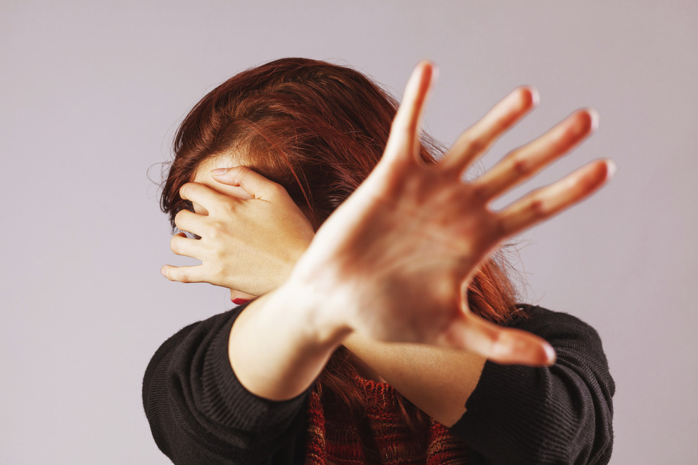 Woman holding up hands to prevent physical abuse.