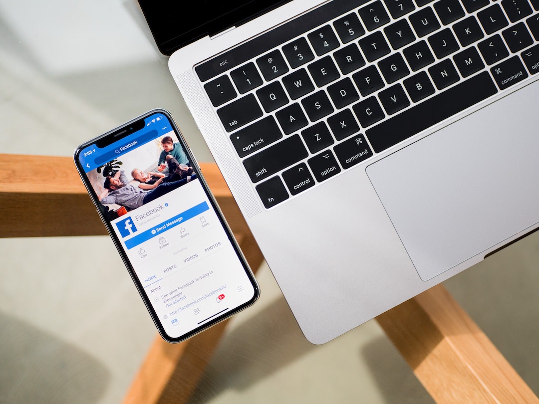 Facebook on mobile phone with laptop computer