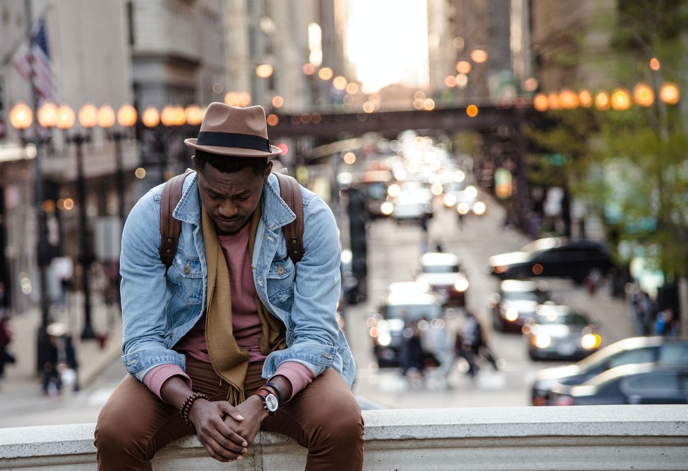 Black man sitting on a bench dealing with grief.