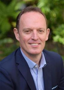 Headshot of Brian King with brown, short hair wearing a blue dress shirt and suit jacket.