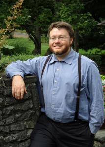 Anderson with brown hair, glasses, beard and blue shirt