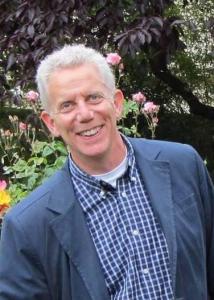 Headshot of Edward Jaenicke outside with short grey, white hair wearing blue dress shirt and suit jacket.