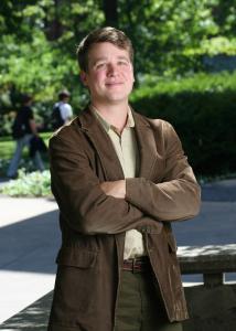 Full shot of Jeremy Staff outside with short brown hair wearing a brown suit jacket.