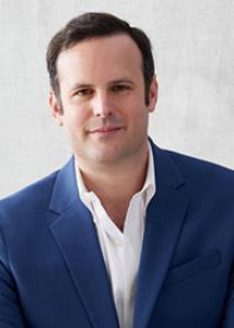Headshot of Max Crowley with blue suit and white button-up shirt and short brown hair.
