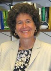 Headshot of Pamela with short brown hair, black and white patterned top, and white jacket.