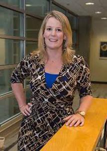 Full shot of Shannon Monnat indoors with long blonde hair wearing a patterned dress.